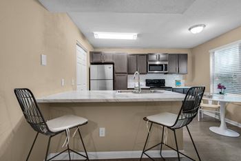An in-unit kitchen with a granite countertop and a dining table.